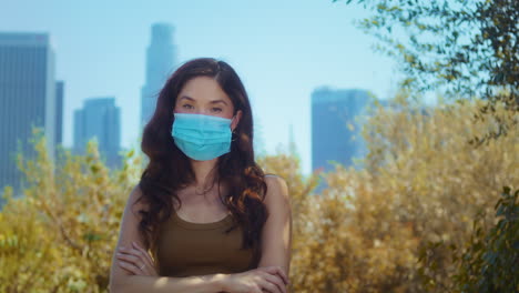 Asian-model-in-mask-looking-camera-in-park-closeup.-Brunette-care-of-health.