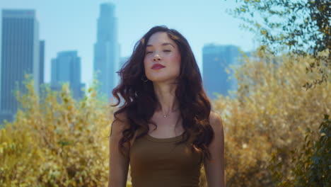 Woman-looking-back-on-skyscrapers-standing-in-park.-Asian-lady-enjoy-city-view.