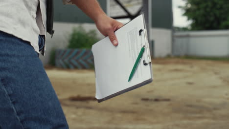 Manager-walking-farming-facility.-Unknown-businessman-holding-clipboard-closeup.