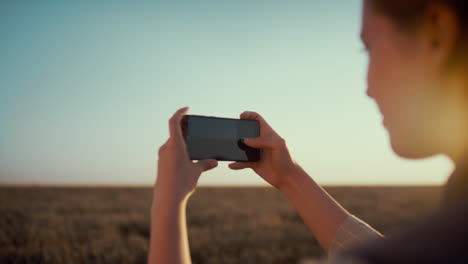 Girl-taking-field-picture-at-countryside.-Female-hands-hold-smartphone-closeup.