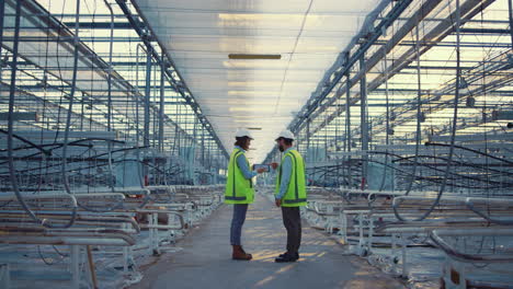 Two-factory-workers-device-displaying-new-safety-data-engineers-discussing