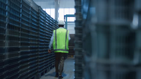Man-warehouse-employee-walking-among-blue-pallets-analysing-shipment-products