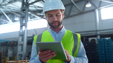 Portrait-focused-factory-employee-checking-tablet-information-inspecting-storage