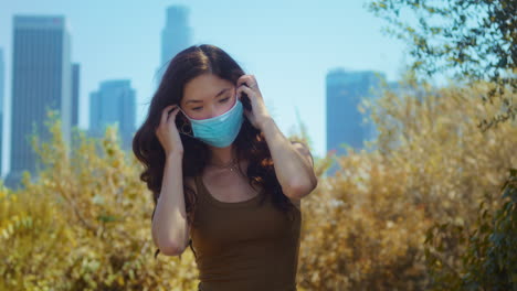 Girl-covering-face-with-mask-in-park-closeup.-Asian-model-wearing-protection.