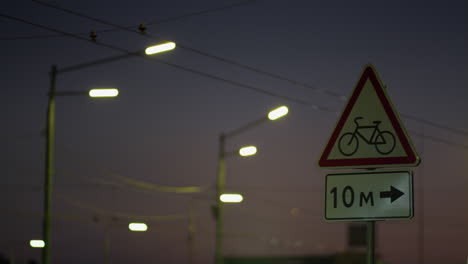 Warning-red-roadsign-at-night-highway-closeup.-Cars-headlight-beams-flashing.