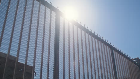 Modern-city-fence-on-sunlight-bottom-view.-Metal-barrier-against-city-background