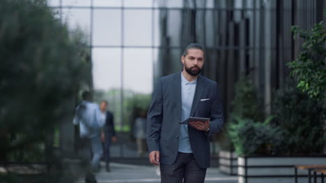 Focused-manager-walking-with-tablet-at-modern-office-building.-Career-people