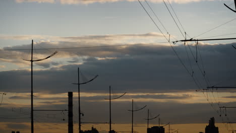Graue,-Bauschige-Wolken-Ziehen-Bei-Sonnenuntergang-über-Die-Stadt.-Elektrokabel,-Laternen.
