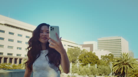 Lady-tourist-looking-on-camera-making-selfie.-Model-posing-on-city-street.