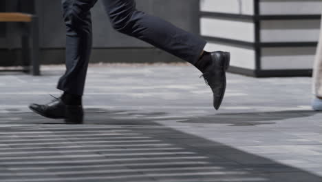 Businessman-legs-running-city-street-in-black-shoes-closeup.-Morning-commute