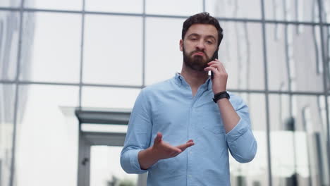 Attractive-man-ending-phone-call-outside-office.-Serious-client-reject-project.