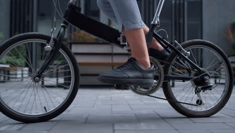 Closeup-worker-legs-pedaling-at-downtown-district.-Eco-friendly-transportation.