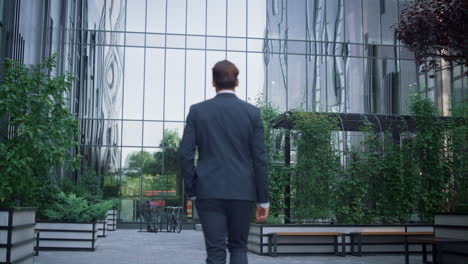 Confident-businessman-walking-business-center-garden-alone.-Success-concept.