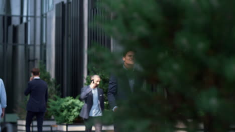Satisfied-businessman-walking-downtown-district-in-suit-looking-in-distance.