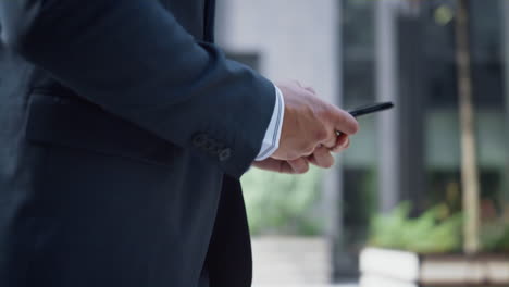 Businessman-hands-holding-phone-texting-closeup.-Man-using-smartphone-walking.