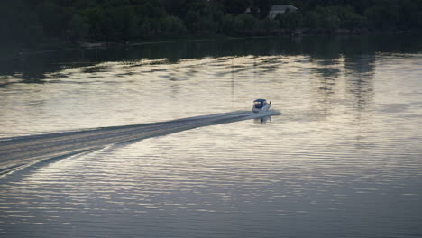 Motorboot,-Das-Am-Abend-Einen-Dunklen-Fluss-Am-Grünen-Baumufer-Fährt,-Drohnenaufnahme.