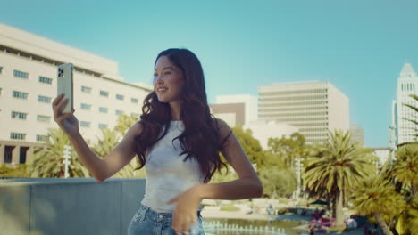 Smiling-girl-posing-on-camera-closeup.-Asian-woman-making-selfie-on-cityscape.