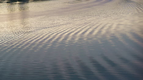 Wavy-river-ripples-flowing-drone-shot.-Sunlight-glares-moving-at-calm-pace.