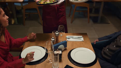Kellner-Serviert-Einem-Multiethnischen-Paar-Restaurantessen-Bei-Einem-Romantischen-Abendessen.