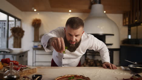 Man-cooking-pizza-in-italian-food-restaurant.-Chef-adding-ingredients-on-pastry.
