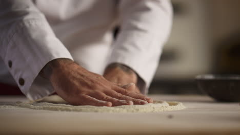 Baker-hands-cooking-dough-pizza-on-flour-wooden-board-in-kitchen-restaurant.