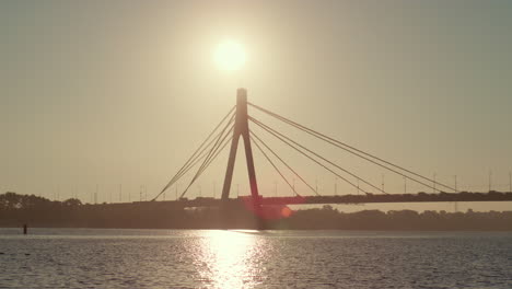Flussbrückensilhouette-An-Einem-Sommertag-Mit-Klarem-Himmel.-Wasser-Reflektiert-Goldenes-Sonnenlicht