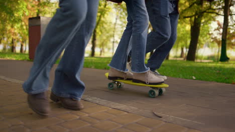 Mädchenbeine-Reiten-Skateboard-Im-Park,-Nahaufnahme.-Unbekannte-Eltern-Unterstützen-Das-Kind.