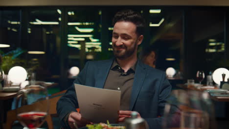 Smiling-man-looking-menu-on-restaurant-date.-Guy-sitting-at-fancy-dinner-table.