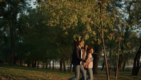 Family-walking-autumn-park-holding-hands-together-in-evening-golden-sunlight.