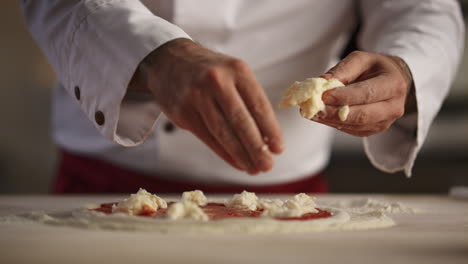 Pizzabäcker-Kocht-Essen-Im-Restaurant.-Mannhände-Legen-Mozzarella-Käse-In-Die-Küche