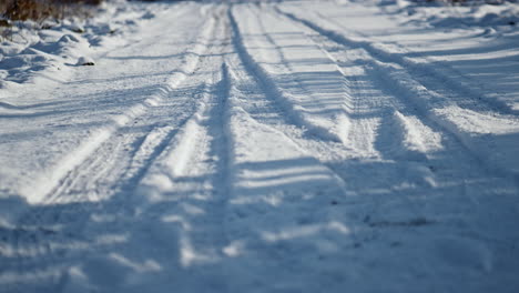 Snowy-road-wheel-marks-sunny-winter-day-close-up.-Snow-covered-rural-roadway.