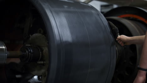 Tyre-production-worker-handling-rubber-tape-on-round-modern-machine-close-up