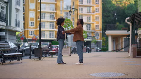 Happy-couple-touching-hands-learning-dancing-moves-together-on-city-street.