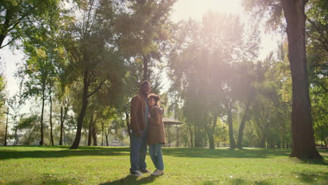 Happy-child-father-standing-together-on-green-park-field-in-golden-sunlight.