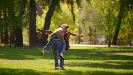 Playful-father-piggybacking-daughter-enjoying-family-weekend-in-sunny-park.