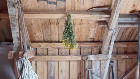 Garden-Tools-And-A-Bunch-Of-Dried-Yellow-Flowers-Hanging-Upside-Down-On-A-Wooden-Farmhouse-In-Norway---High-Angle-Shot