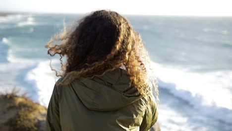 Slow-motion-of-a-girl-looking-at-the-beach-with-hair-flying-with-the-wind