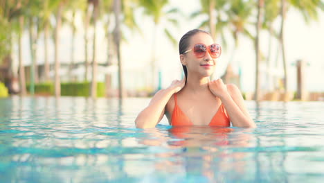 An-attractive-young-woman-emerges-from-a-resort-swimming-pool