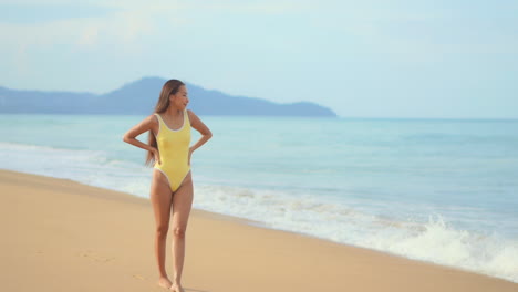 Charming-asian-girl-in-yellow-swimsuit-walks-on-beach