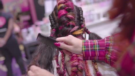 Professional-hairdresser-is-combs-colorful-braided-hairstyle-to-make-it-look-with-more-volume-slow-motion