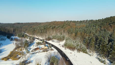 Cars-Traveling-On-Long-And-Winding-Road-Through-Snow-covered-Forest-In-Gdansk,-Poland