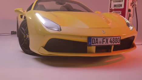 Ferrari-Amarillo-En-El-Estudio-Junto-A-Una-Bomba-De-Gasolina,-La-Cámara-Se-Mueve-Hacia-El-Capó