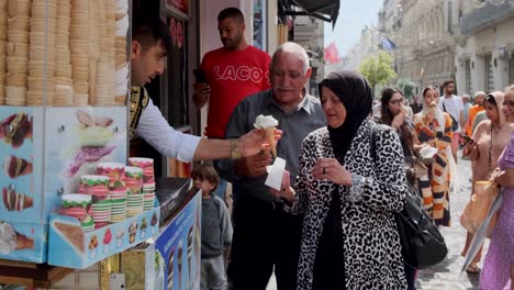 Das-Filmmaterial-Zeigt-Die-Interaktion-Des-Eisverkäufers-Mit-Einem-älteren-Muslimischen-Paar-In-Der-Taksim-straße,-Die-Lachen-Und-Die-Vorführung-Des-Eisverkäufers-Genießen