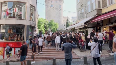 Imágenes-De-Tiro-Inclinado-Muestran-La-Icónica-Torre-De-Galata-En-Estambul,-Turquía,-Con-Turistas-Paseando-Por-Las-Calles-En-Una-Mañana-Soleada