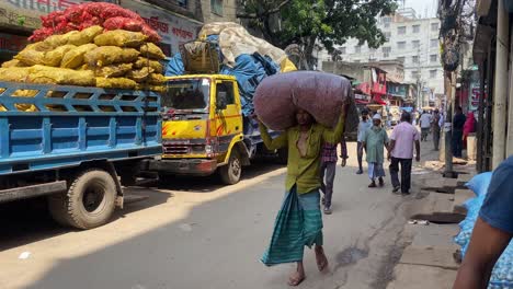 Strong-poor-laborer-man-carrying-food-sack-in-head-to-load-truck-at-street-of-Dhaka,-Bangladesh