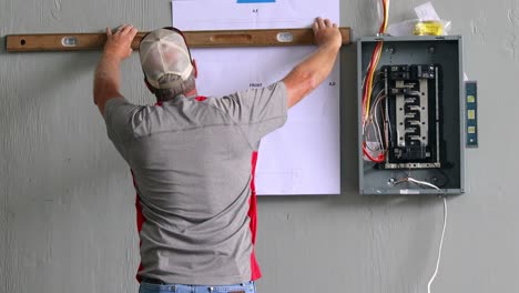 Techniker,-Der-Eine-Wasserwaage-Verwendet,-Um-Die-Platzierung-Der-Steuerstation-In-Bezug-Auf-Die-Schalttafel-Zu-Finden