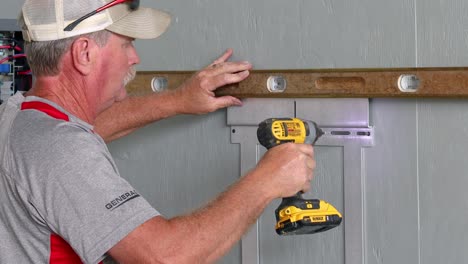 Technician-using-a-level-and-drill-to-install-the-support-bracket-for-the-power-system-control-station