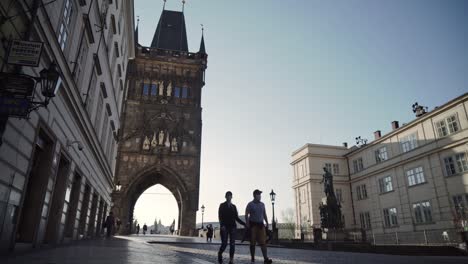 Pareja-O-Pareja-Caminando-Bajo-La-Puerta-De-La-Torre-Del-Puente-De-La-Ciudad-Vieja-En-Praga,-Vista-De-Gran-Angular-Bajo,-República-Checa