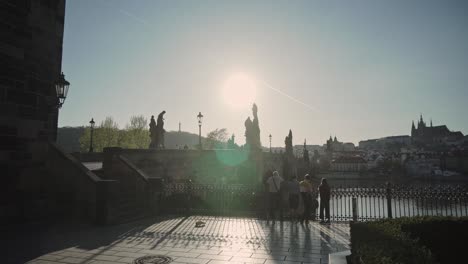 Puente-Charles-O-Karluv-Most-En-Praga-Con-Un-Grupo-De-Personas-Y-Rayos-De-Sol-O-Vigas,-Vista-Matutina