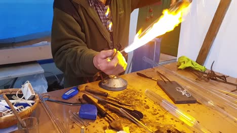 Glassblower-artisan-shaping-the-hot-molten-glass-at-strong-fire-inside-a-workshop